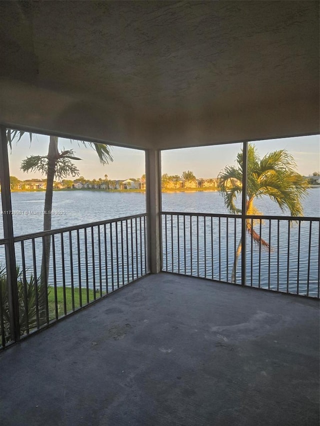 balcony at dusk featuring a water view