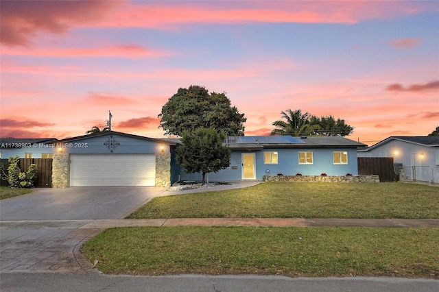 single story home featuring a garage, a yard, and solar panels