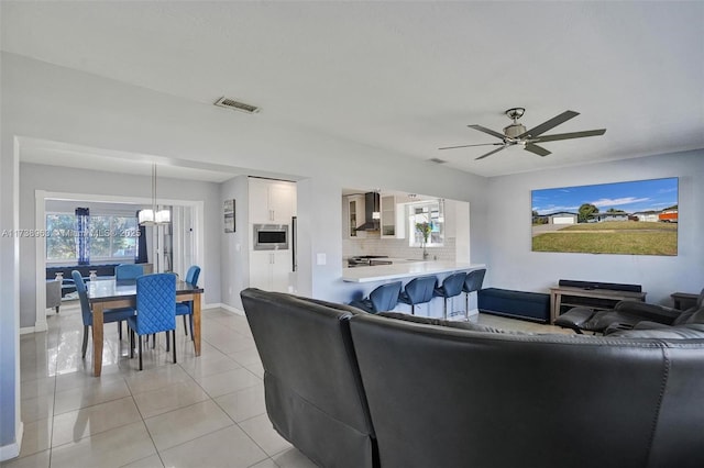 living room featuring ceiling fan with notable chandelier and light tile patterned floors