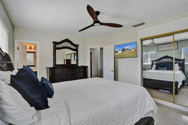 bedroom with connected bathroom, light tile patterned floors, ceiling fan, and a closet