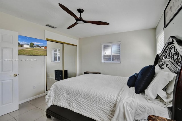 tiled bedroom with multiple windows, ceiling fan, and a closet