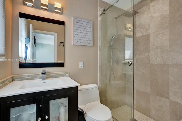 bathroom featuring tasteful backsplash, vanity, toilet, and a shower with shower door