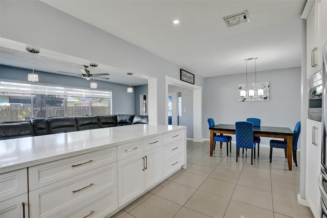 kitchen featuring ceiling fan with notable chandelier, light tile patterned floors, white cabinets, and decorative light fixtures