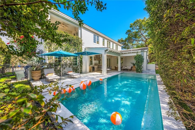 back of property with a fenced in pool, a patio area, fence, and ceiling fan