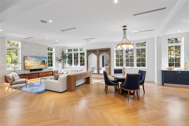 interior space featuring a notable chandelier, ornamental molding, light parquet floors, and brick wall