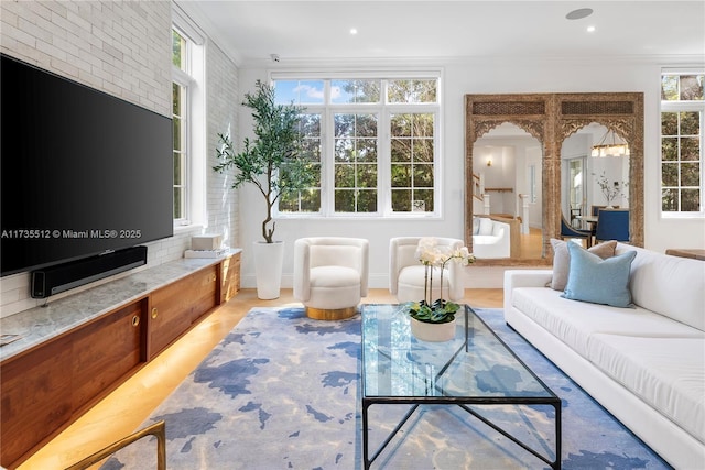 living room featuring arched walkways, brick wall, ornamental molding, and recessed lighting