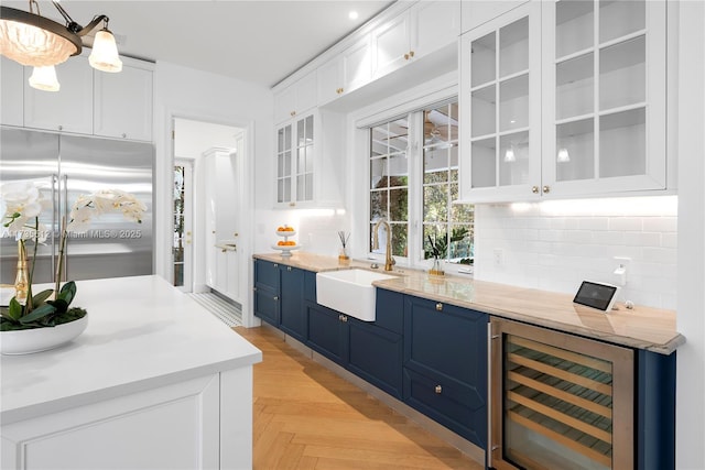 bar featuring built in refrigerator, white cabinetry, sink, and wine cooler