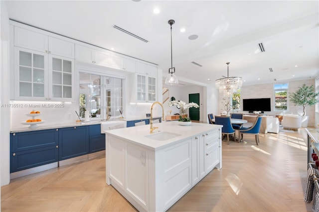 kitchen with blue cabinetry, glass insert cabinets, open floor plan, white cabinets, and a sink