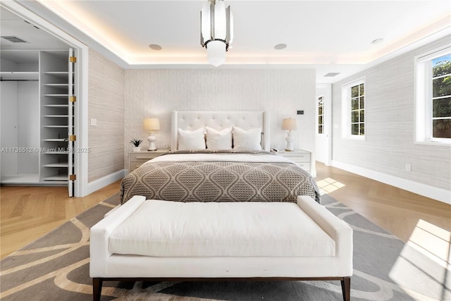 bedroom with a tray ceiling and parquet flooring