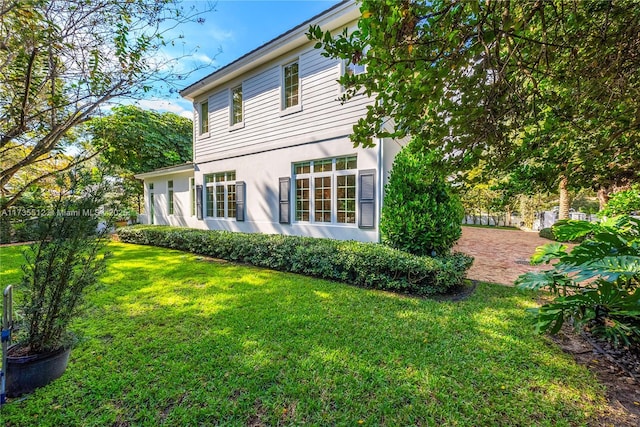 rear view of property featuring a lawn and stucco siding