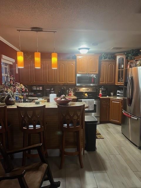 kitchen featuring hanging light fixtures, a kitchen island, a kitchen breakfast bar, and appliances with stainless steel finishes