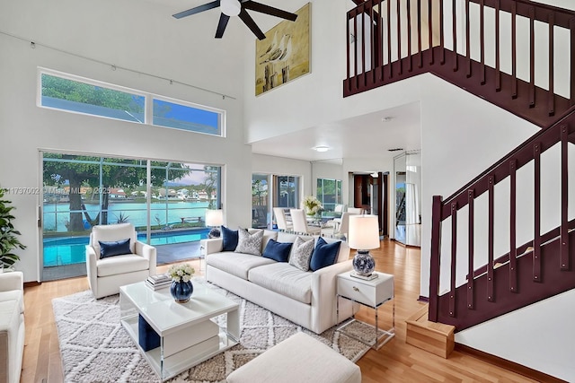 living room featuring hardwood / wood-style floors, a towering ceiling, and ceiling fan