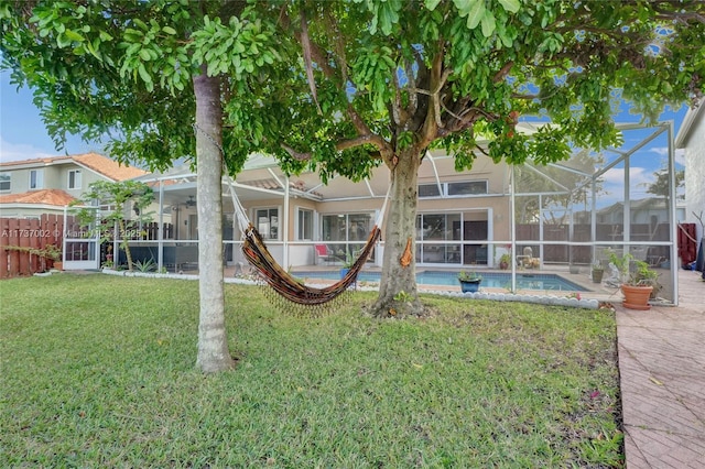 rear view of house with a lanai and a lawn