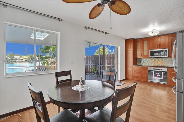 dining room with plenty of natural light, a textured ceiling, and light wood-type flooring