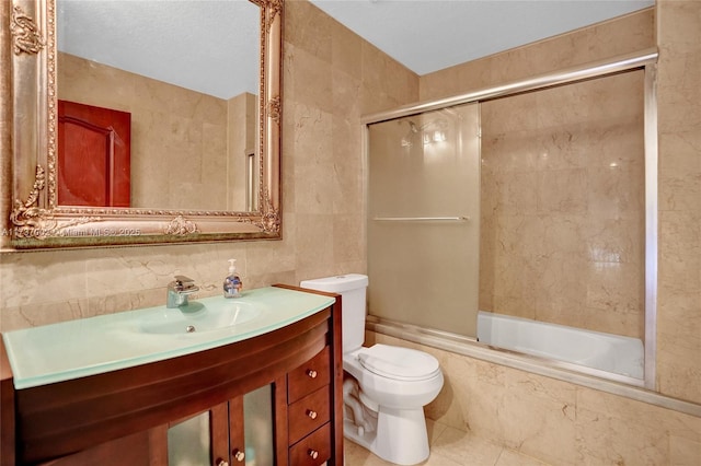 full bathroom with sink, tile walls, bath / shower combo with glass door, tasteful backsplash, and toilet