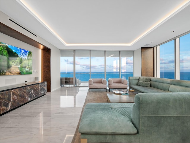 living room featuring expansive windows, a raised ceiling, and a water view