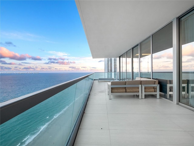 balcony at dusk featuring a water view and an outdoor hangout area