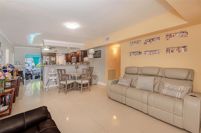 living room featuring light tile patterned flooring, ornamental molding, and ceiling fan