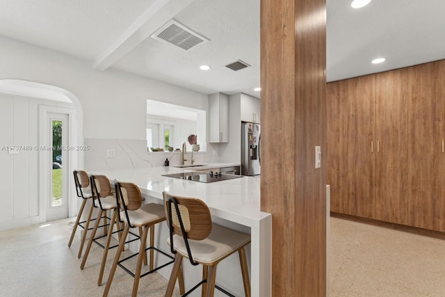 kitchen with a peninsula, visible vents, a breakfast bar, and white cabinets