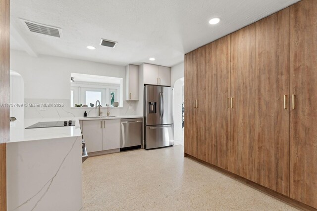 kitchen featuring stainless steel appliances, arched walkways, white cabinetry, and visible vents