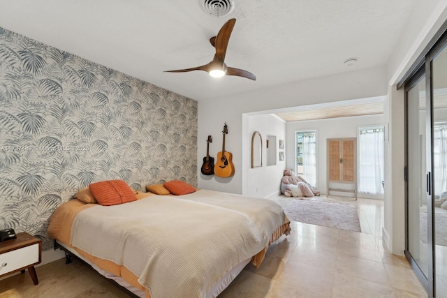 bedroom featuring ceiling fan, an accent wall, visible vents, a closet, and wallpapered walls