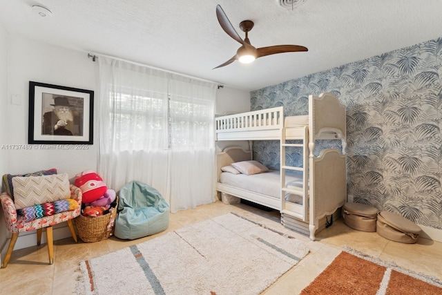 bedroom with a textured ceiling, a ceiling fan, and wallpapered walls