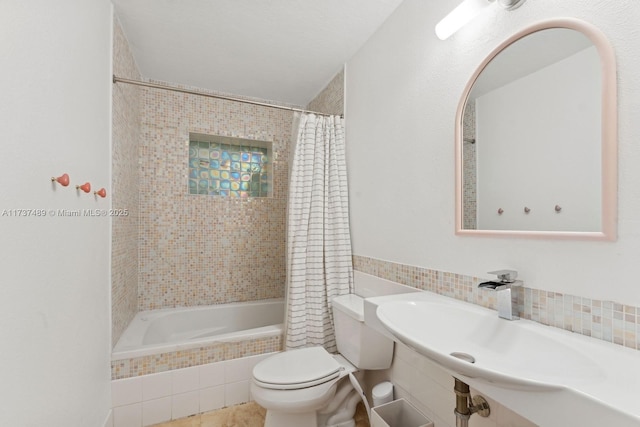 full bath with tiled shower / bath, a textured ceiling, a sink, and toilet