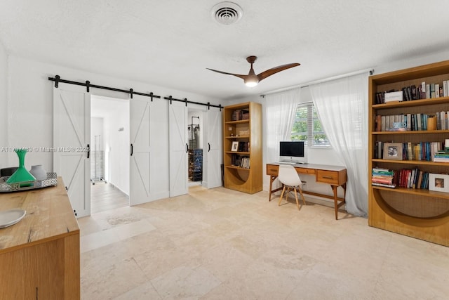 office space with a ceiling fan, visible vents, a textured ceiling, and a barn door