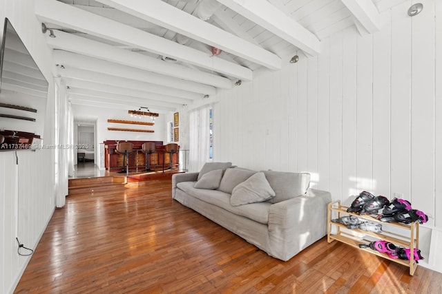 living area with a dry bar, wood finished floors, and beamed ceiling