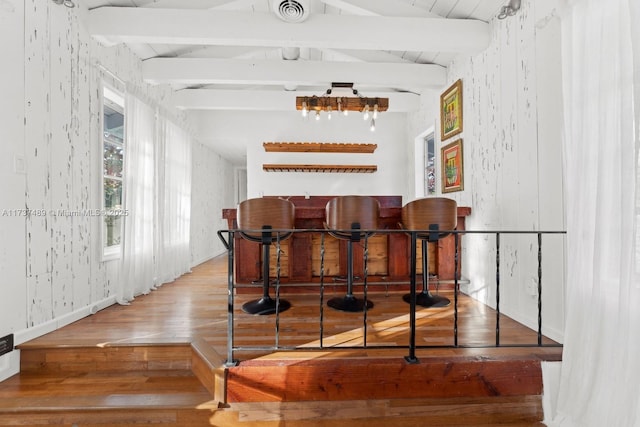 bar featuring visible vents, lofted ceiling with beams, a bar, and wood finished floors