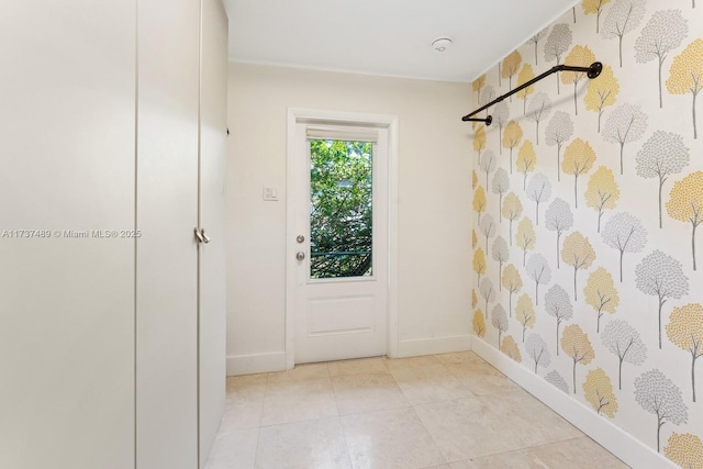 doorway featuring light tile patterned floors and baseboards