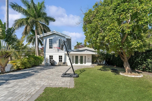 view of front of property featuring a front yard, decorative driveway, and french doors