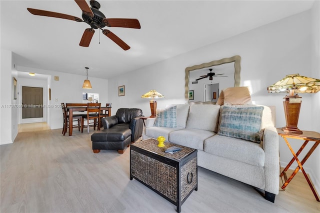 living room with baseboards, ceiling fan, and light wood-style flooring