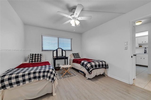 bedroom with baseboards, ceiling fan, light wood-style flooring, and a sink