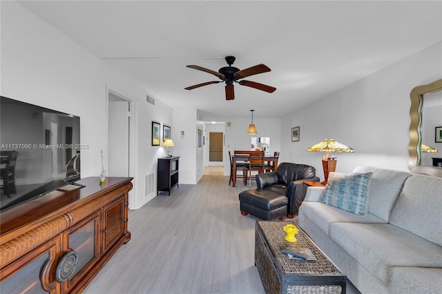 living room with visible vents, a ceiling fan, light wood-style flooring, and baseboards