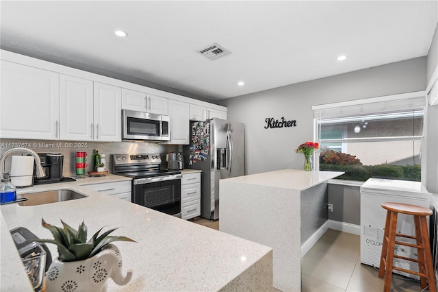 kitchen featuring tasteful backsplash, visible vents, white cabinets, stainless steel appliances, and a sink