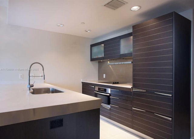 kitchen featuring black electric cooktop, stainless steel oven, and sink