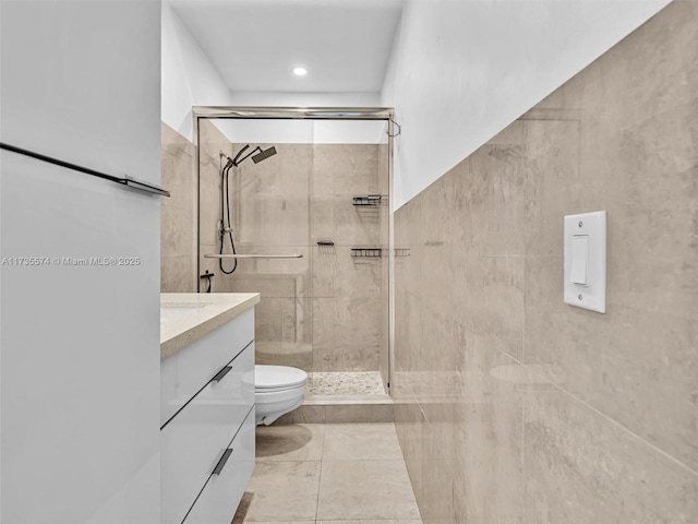 bathroom featuring vanity, a shower with door, and toilet