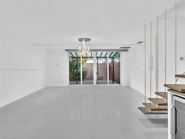 unfurnished living room featuring wine cooler, a chandelier, and light tile patterned floors