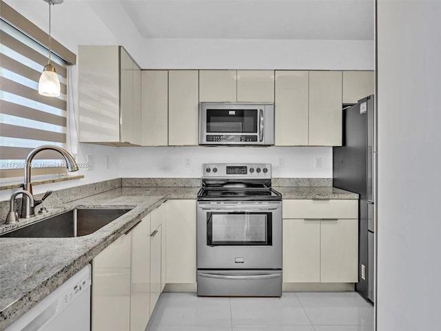 kitchen with sink, decorative light fixtures, stainless steel appliances, and cream cabinetry