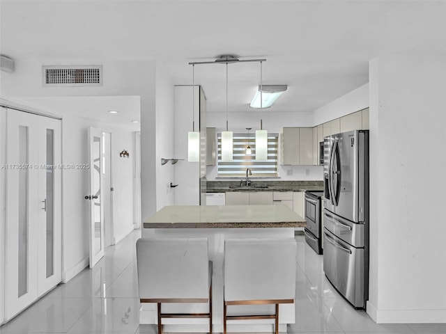 kitchen with sink, decorative light fixtures, light tile patterned floors, appliances with stainless steel finishes, and a kitchen breakfast bar