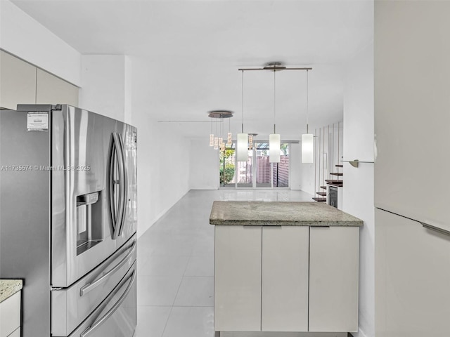 kitchen featuring stainless steel refrigerator with ice dispenser, stone counters, decorative light fixtures, and light tile patterned floors