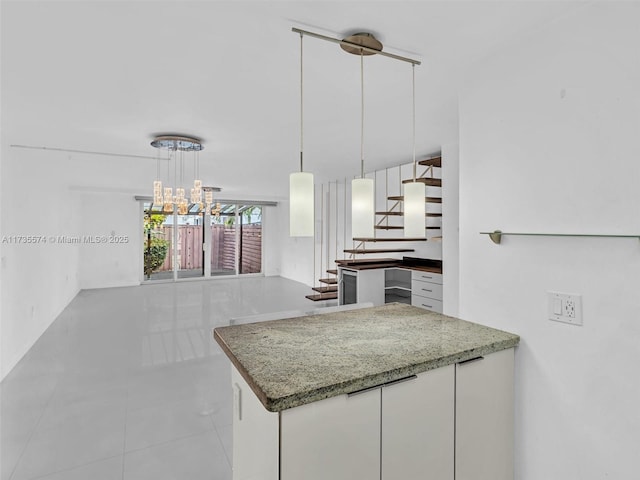 kitchen with light tile patterned flooring, white cabinetry, stone counters, a notable chandelier, and pendant lighting