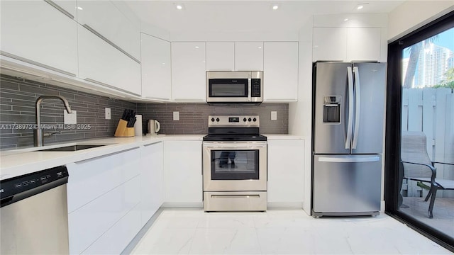 kitchen featuring tasteful backsplash, appliances with stainless steel finishes, sink, and white cabinets