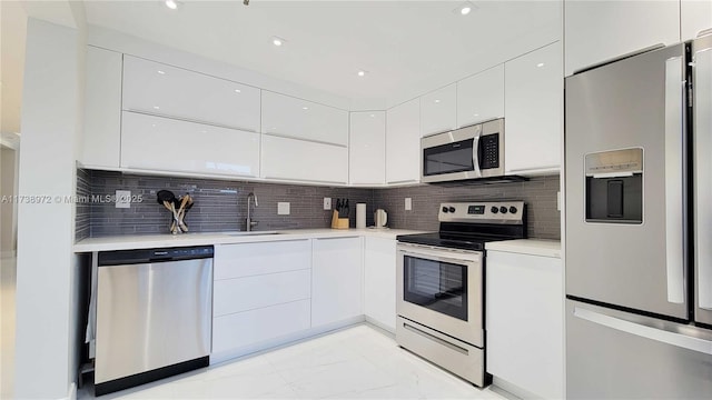 kitchen with tasteful backsplash, sink, stainless steel appliances, and white cabinets