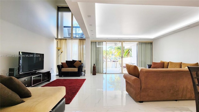 living room with floor to ceiling windows and a raised ceiling