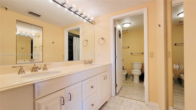 bathroom with a bidet, vanity, a textured ceiling, tile patterned floors, and toilet