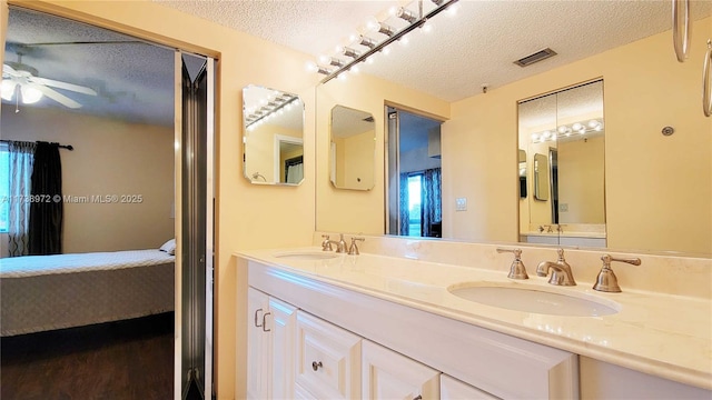 bathroom with vanity, ceiling fan, hardwood / wood-style flooring, and a textured ceiling