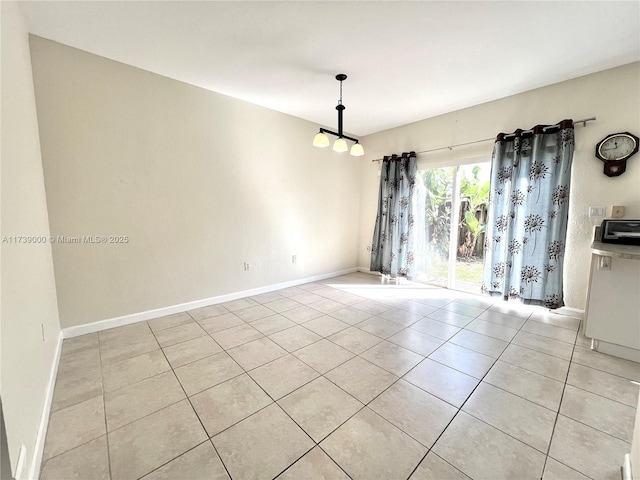 tiled empty room featuring an inviting chandelier