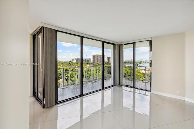 empty room with a wall of windows, plenty of natural light, and light tile patterned floors